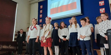 Powiększ grafikę: uczniowie na scenie śpiewają pieśni patriotyczne
