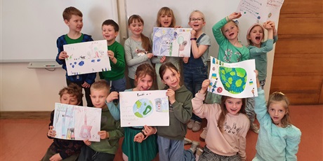 Powiększ grafikę: grupa uczniów trzyma w ręce swoje prace o tematyce ekologicznej 