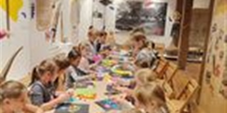 Powiększ grafikę: Dzieci w sali muzeum   przyklejają kawałki kolorowej bibuły do swoich listków.